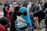 Perempuan Afghanistan Menggendong Anaknya di Tengah Orang-orang yang Menunggu Bantuan Kemanusiaan. Foto: Antara/Reuters.