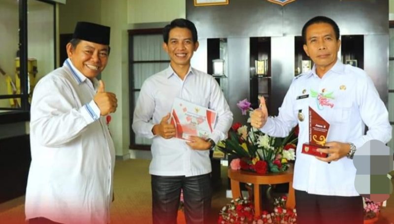 Sekda Mura Hermon (kanan) didampingi Kadis Kominfo SP Mura Bimo Santoso  saat menyerahkan piagam, piala dan uang pembinaan kepada Hendra Efhendy juara II lomba vlog FBIM. (Foto: suroso/1tulah.com)