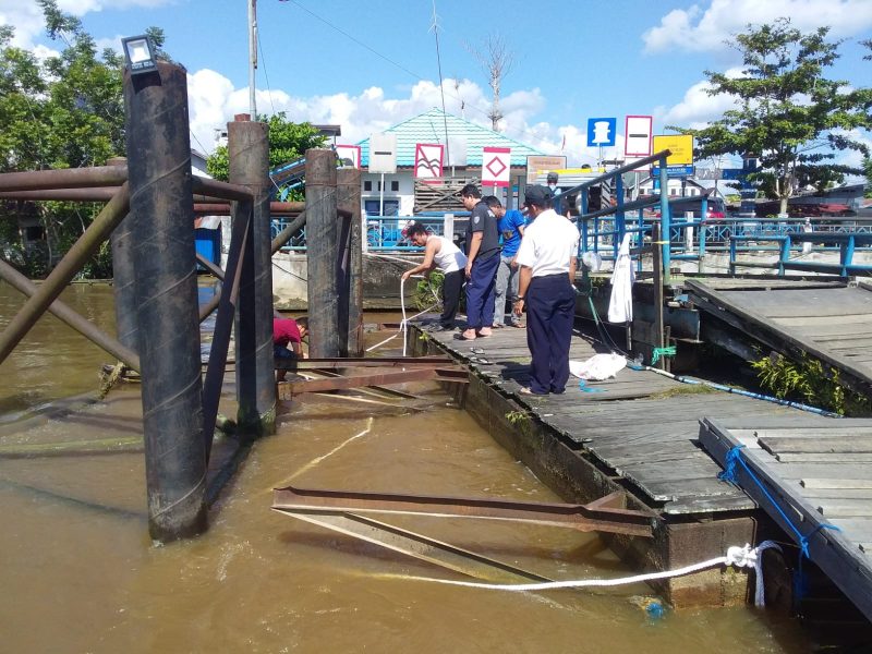 Petugas Dermaga Buntok saat mengikatkan tali penahan ke tiang dermaga, untuk mengantisipasi hanyutnya ponton dermaga. foto.Alifansyah/1tulah.com

