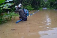 Warga saat kesulitan melintas di jalan yang terendam banjir.Foto.Delia/1tulah.com