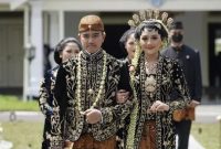 Putra bungsu Presiden Joko Widodo, Kaesang Pangarep (kiri) bersama Erina Gudono (kanan) berjalan menuju lokasi resepsi Tasyakuran di Pura Mangkunegaran, Solo, Jawa Tengah, Minggu. Sumber foto : suara.com