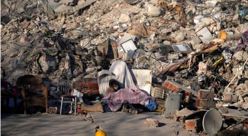 Seorang pria tidur di depan bangunan yang hancur di Kahramanmaras, tenggara Turki, 13 Februari 2023. (Foto: AP)