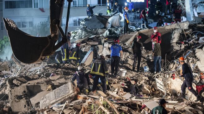 Relawan mencari korban selamat di sebuah bangunan yang runtuh setelah gempa bumi yang kuat melanda pantai barat Turki dan sebagian Yunani, di Izmir, Sabtu (31/10/2020). Sumber foto : bali.suara.com
