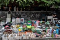 Seorang pedagang (kanan) menjual peralatan dapur bekas menunggu pelanggan di pasar barang bekas di Surabaya, 1 Februari 2023. (JUNI KRISWANTO/AFP)