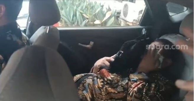 Ketua KPK Firli Bahuri berusaha hindari sorotan wartawan hingga menutupi wajahnya di dalam mobil. Momen itu terjadi setelah Firli menjalani pemeriksaan di Bareskrim Polri terkait kasus dugaan pemersaan terhadap Syahrul Yasin Limpo (SYL). (Suara.com/M Yasir)