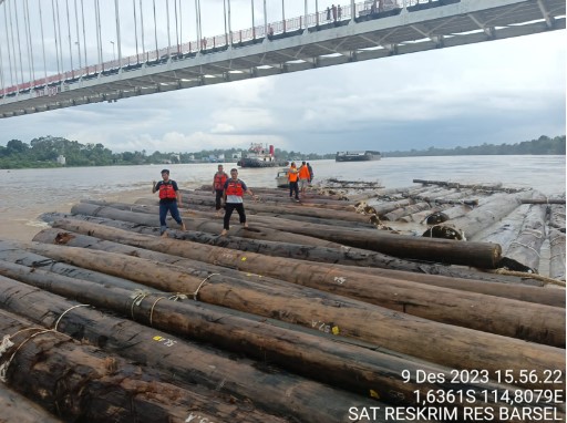 Personel Polres Barsel saat mengamankan dan memeriksa rakit kayu yang diduga menabrak render tiang jembatan Kalahien,Sabtu (9/12/2023). Alifansyah/1tulah.com