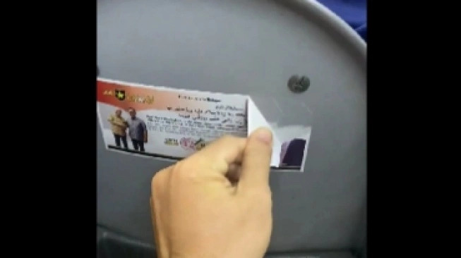 Penumpang transjakarta cabut sticker kampanye. (foto: suara.com)