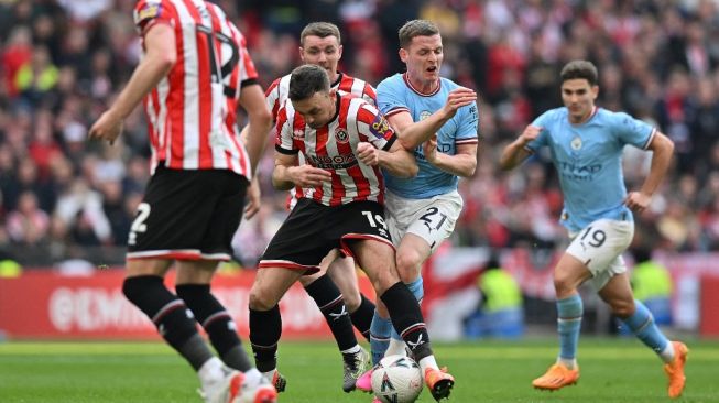 Bek Sheffield United Jack Robinson bentrok dengan bek Manchester City Sergio Gomez selama pertandingan semifinal Piala FA 2022-2023 antara Manchester City vs Sheffield United di Stadion Wembley di barat laut London pada 22 April 2023 (sumber: suara.com)