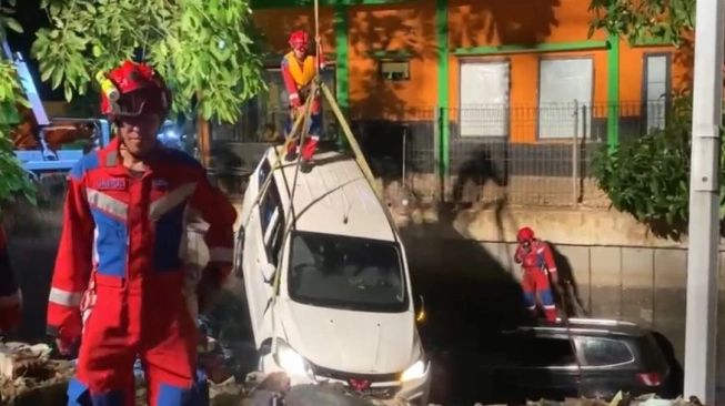 Petugas sedang mengevakuasi mobil di aliran Waduk Jatipulo Tomang (sumber: suara.com)