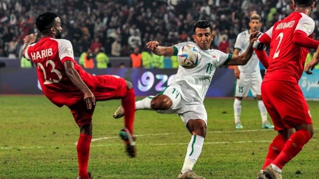 Gelandang timnas Irak Amjad Attwan (tengah) menendang bola pada pertandinganfinal Piala Teluk Arab ke-25 antara Irak vs Oman di Stadion Internasional Basra di kota selatan Irak pada 19 Januari 2023. (sumber: suara.com)