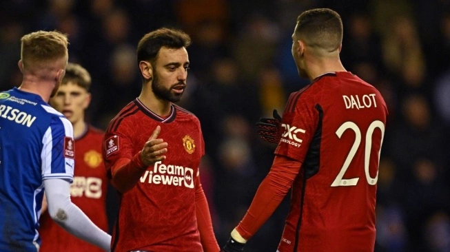 Gelandang Manchester United asal Portugal #08 Bruno Fernandes (tengah) melakukan selebrasi bersama bek asal Portugal #20 Diogo Dalot (kanan) setelah mencetak gol kedua timnya dari titik penalti pada pertandingan putaran ketiga Piala FA 2023-2024 antara Wigan Athletic vs Manchester United di Stadion DW di Wigan, barat laut Inggris pada 8 Januari 2024 (sumber: suara.com)