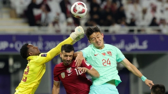 Penjaga gawang timnas Qatar #22 Meshaal Barsham melompat untuk meninju bola saat beknya #16 Boualem Khoukhi dan bek China #24 Jiang Shenglong bersaing selama pertandingan terakhir Grup A Piala Asia 2023 antara Qatar vs China di Stadion Internasional Khalifa di Doha pada 22 Januari 2024.  (sumber: suara.com)