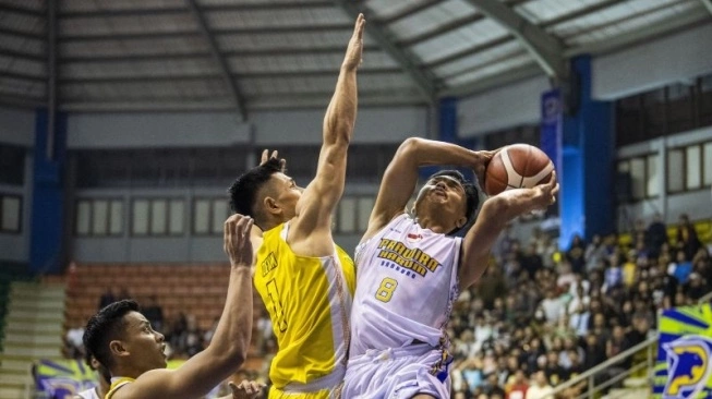 Pebasket Prawira Harum Bandung Yudha Saputera (kanan) berusaha melakukan lay up dibayangi pebasket Kesatria Bengawan Solo Samuel D Susanto (tengah) saat pertandingan Indonesian Basketball League (IBL) 2024 di GOR C-tra Prawira Arena, Bandung, Jawa Barat, Minggu (14/1/2024).  (sumber: suara.com)