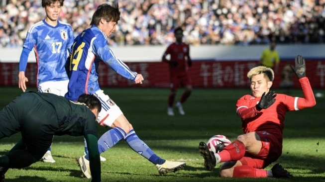 Suphanan Bureerat (kanan) dari Thailand meluncur untuk memblokir tembakan pemain Jepang Junya Ito (kedua dari kiri) selama pertandingan persahabatan sepak bola internasional di Hari Tahun Baru 2024 antara Jepang vs Thailand di Stadion Nasional di Tokyo pada 1 Januari 2024 (sumber: suara.com)