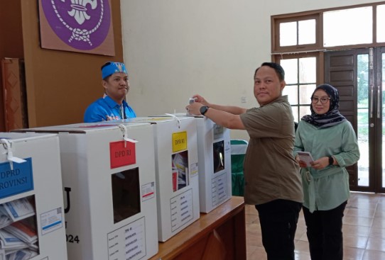 Pj. Bupati Barsel, H. Deddy Winarwan bersama istri Hj. Erna Ardiana saat memasukan surat suara ke kekotak suara usai menggunakan hak pilihnya, bertempat di TPS 40, Jalan Pahlawan, Buntok, Rabu (14/2/2024). Foto. Alifansyah/1tulah.com