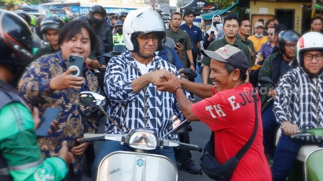 Capres nomor urut satu, Anies Baswedan menyalami warga saat mengendarai Vespa usai membeli Takjil untuk berbuka puasa di Pasar Takjil Benhil, Jakarta, Rabu (20/3/2024) (sumber: suara.com)