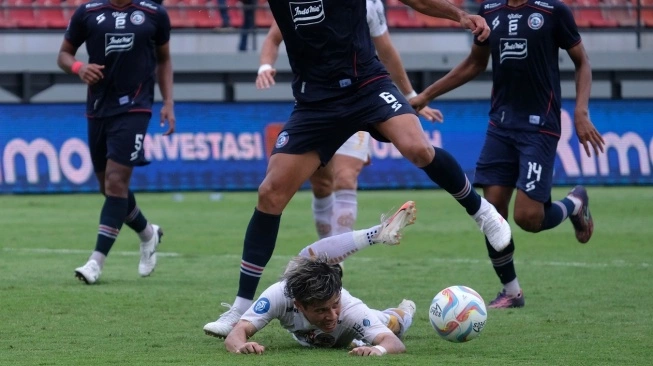 Pesepak bola Persija Jakarta Ryo Matsumura (bawah) terjatuh saat berebut bola dengan pesepak bola Arema FC Julian Guevara (atas) pada pertandingan BRI Liga 1 di Stadion Kapten I Wayan Dipta, Gianyar, Bali, Senin (26/2/2024). Arema FC mengalahkan Persija Jakarta dengan skor 3-2. (sumber: suara.com)