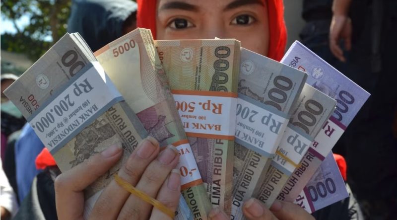 Seorang perempuan memperlihatkan uang yang akan dibagikan kepada para kerabat untuk Idul Fitri di Malang, Jawa Timur, 15 Juni 2016. (Foto: Aman Rochman/AFP/ilustrasi)