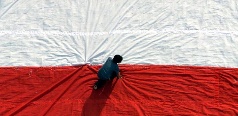 Seorang pria mempersiapkan bendera raksasa sebelum mengibarkannya pada perayaan hari kemerdekaan di Universitas Kristen Petra di Surabaya, Jawa Timur. Pemerintah mungkin akan menawarkan kewarganegaraan ganda bagi orang-orang keturunan Indonesia. (Foto: REUTERS/Sigit Pamungkas)