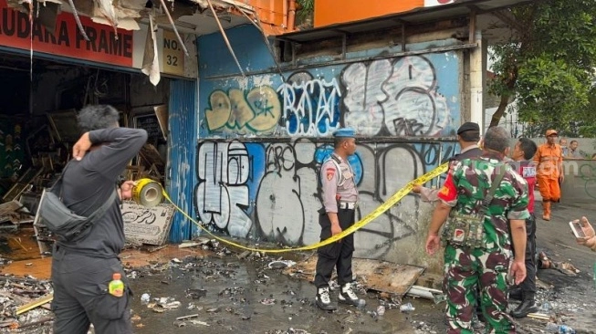 Penampakan aparat gabungan saat memasang police line di Ruko Saudara Frame dan Gallery, di Jalan Mampang Prapatan Raya, Jakarta Selatan usai ludes terbakar dan menewaskan tujuh korban jiwa.  (sumber: suara.com)