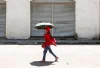 Seorang perempuan menggunakan payung untuk berlindung dari terik matahari saat cuaca panas di Manila pada 28 April 2024. (Foto: AFP)