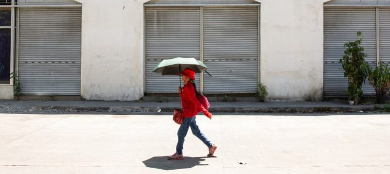 Seorang perempuan menggunakan payung untuk berlindung dari terik matahari saat cuaca panas di Manila pada 28 April 2024. (Foto: AFP)