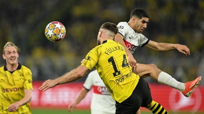 Penyerang Dortmund asal Jerman Niclas Fuellkrug menyundul bola di samping bek Maroko Paris Saint-Germain Achraf Hakimi pada pertandingan sepak bola leg pertama semifinal Liga Champions UEFA antara Borussia Dortmund dan Paris Saint-Germain (PSG) pada 1 Mei 2024 di Dortmund. (sumber: suara.com)