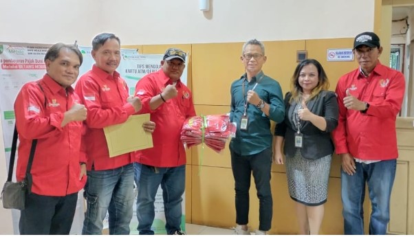 Pimpinan Bank Kalteng Cabang Buntok, Muhammad Rifai didampingi stafnya (tengah kanan) saat menyerahkan bantuan seragam kepada Ketua PWRI Kabupaten Barsel, Fatli bersama anggotanya, Kamis (30/5/2025). Foto. Alifansyah/1tulah.com