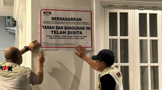 Penyidik Komisi Pemberantasan Korupsi (KPK) menempelkan pengumuman penyitaan di tembok rumah terdakwa Muhammad Hatta, mantan Direktur Alat dan Mesin Pertanian Kementerian Pertanian (Kementan) tahun 2023 atas perkara dugaan pemerasan dan korupsi di Jalan Bumi Harapan, Kota Parepare, Sulawesi Selatan, Minggu (19/5/2024) (sumber: suara.com)