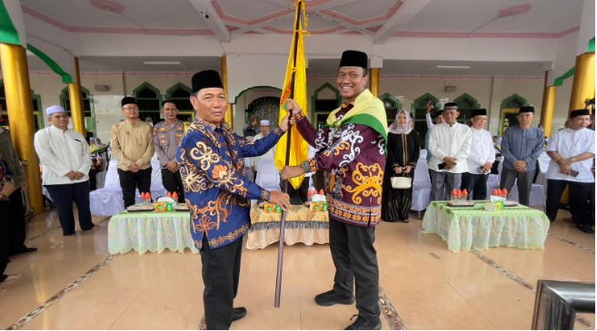 Asisten III, Mirwansyah saat menyerahkan bendera Kabupaten Barsel kepada Ketua rombongan CJH sebelum melepas keberangkatan CJH ke Tanah Suci Mekkah, bertempat di halaman Mesjid Agung Baiturram, Buntok, Minggu (19/5/2024). Foto. Alifansyah/1tulah.com