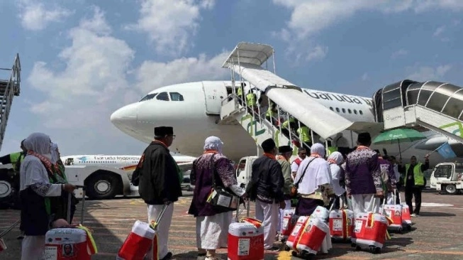 Sejumlah jamaah calon haji Kloter 18 Embarkasi Solo, di Solo, Jawa Tengah, Kamis (16/5/2024), mengantre memasuki pesawat Garuda Indonesia di Bandara Adi Soemarmo Solo menuju Bandara Amir Muhammad bin Abdul Aziz (AMAA), Madinah.  (sumber: suara.com)