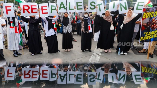 Massa mengangkat poster saat Aksi Bela Palestina di Kawasan Patung Kuda, Jakarta, Minggu (9/6/2024).  (sumber: suara.com)