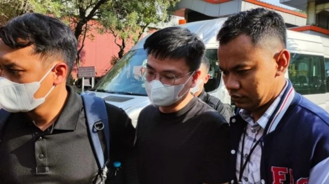 Dittipidsiber Bareskrim Polri menjemput tersangka penipuan daring SZ, warga negara China yang ditangkap di Abu Dhabi, dibawa ke Indonesia melalui Bandara Soekarno-Hatta, Kamis (27/6/2024).  (sumber: suara.com)