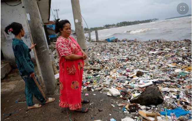 Solikah, 58, dan Cartini, 35, mengamati sampah, sebagian besar plastik dan sampah rumah tangga, yang menutupi pantai di lingkungan mereka di desa nelayan Teluk, Pandeglang, Banten, Maret 15, 2024. (Foto: REUTERS/Willy Kurniawan)
