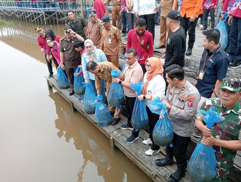 Pj Bupati Muhlis bersama pejabat lain saat melakukan tebar bibit ikan di DAM Trinsing, Selasa (16/7/2024).Foto.M Gazali.1tulah.com