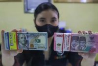 Petugas menunjukkan mata uang Rupiah dan Dolar AS di tempat penukaran uang Dolar Indo, Jakarta, Kamis (20/10/2022). [Suara.com/Alfian Winanto]