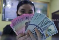 Petugas menunjukkan mata uang Rupiah dan Dolar AS di tempat penukaran uang Dolar Indo, Jakarta, Kamis (20/10/2022). [Suara.com/Alfian Winanto]