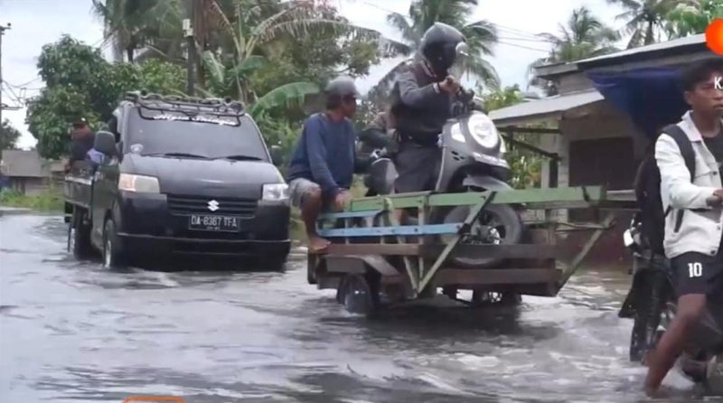 Banyak pengguna motor mengalami mogok saat berusaha menerjang banjir, hal tersebut menjadi peluang usaha bagi Rahman dan 11 rekannya yang lain untuk membuat jasa angkutan penyeberangan menggunakan 5 buah gerobak milik mereka di Desa Kurau, Kecamatan Kurau, Tanah Laut (Tala), Kalsel, hingga saat ini ketinggian masih mencapai 40-50 cm, pada Senin, 26 Januari 2025. Foto: Warga Kurau
