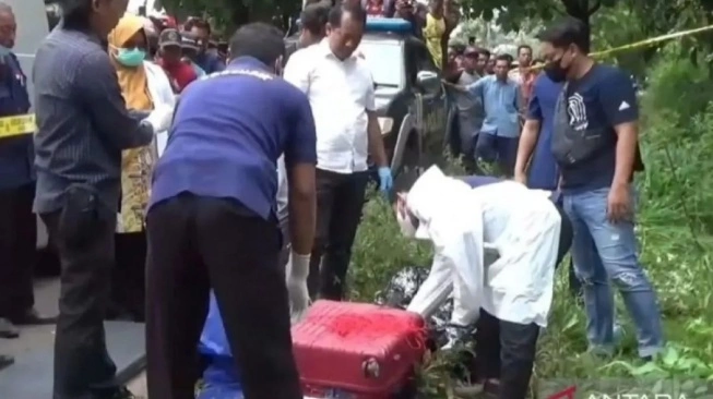 Petugas Polres Ngawi dan RSUD dr Soeroto mengevakuasi jasad wanita dalam koper merah yang ditemukan di Desa Dadapan, Kecamatan Kendal, Kabupaten Ngawi, Jatim, Kamis (23/1/2025) (sumber: suara.com)