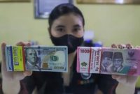 Petugas menunjukkan mata uang Rupiah dan Dolar AS di tempat penukaran uang Dolar Indo, Jakarta, Kamis (20/10/2022). [Suara.com/Alfian Winanto]