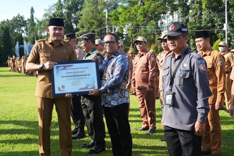 Bupati Tanah Laut (Tala), H Rahmat Trianto, menyerahkan penghargaan atas efisiensi anggaran pelaksanaan Pilkada serta apresiasi terhadap kinerja Organisasi Perangkat Daerah (OPD) dan desa-desa yang berprestasi usai pelaksanaan apel gabungan di halaman Kantor Bupati, Senin, 14 April 2025. Foto: MC Tala