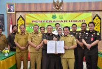 Bupati Kapuas HM Wiyatno saat memberikan hibah secara simbolis kepada Kepala Kejaksaan Negeri Kapuas Luthcas Rohman pada acara penyerahan hibah kepada Kejaksaan Negeri Kapuas yang berlangsung di Aula Kejaksaan Negeri Kapuas, Senin (21/04/2025).