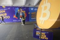 Warga melintas dengan latar logo Bitcoin di Terowongan Kendal, Jakarta, Selasa (24/9/2024). [Suara.com/Alfian Winanto]