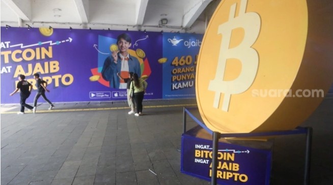 Warga melintas dengan latar logo Bitcoin di Terowongan Kendal, Jakarta, Selasa (24/9/2024). [Suara.com/Alfian Winanto]