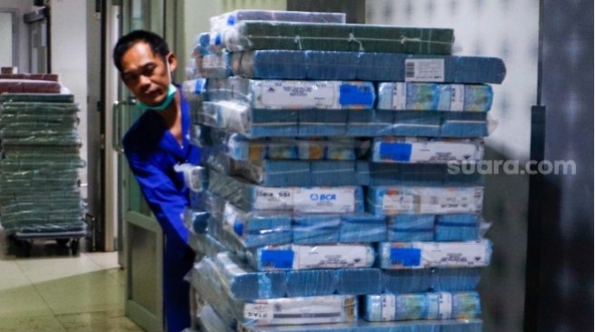 Karyawan mengecek tumpukan uang tunai di cash pooling Plaza Bank Mandiri, Jakarta, Kamis (1/8/2024). [Suara.com/Alfian Winanto]