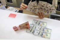 Petugas salah satu tempat penukaran mata uang asing menunjukkan uang rupiah dan dolar AS, Jakarta, Selasa (14/1/2025). [Suara.com/Alfian Winanto]