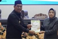 Bupati Barito Utara H Shalahuddin menyerahkan materi rapat kepada Ketua DPRD Hj Mery Rukaini. Foto: Diskominfosandi Barut