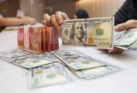 Ilustrasi petugas salah satu tempat penukaran mata uang asing menunjukkan uang rupiah dan dolar AS, Jakarta. [Suara.com/Alfian Winanto] 