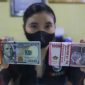 Petugas menunjukkan mata uang Rupiah dan Dolar AS di tempat penukaran uang, Jakarta. [Suara.com/Alfian Winanto] 