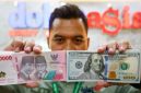 Petugas salah satu tempat penukaran mata uang asing menunjukkan uang rupiah dan dollar AS di Jakarta, Selasa (19/5/2026). [Suara.com/Alfian Winanto] 